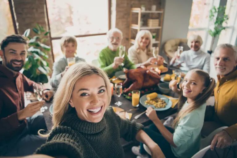 Events photo of big family sit feast dishes table around roasted turkey multi generation relatives making group selfies raising wine glasses juice in living room indoors